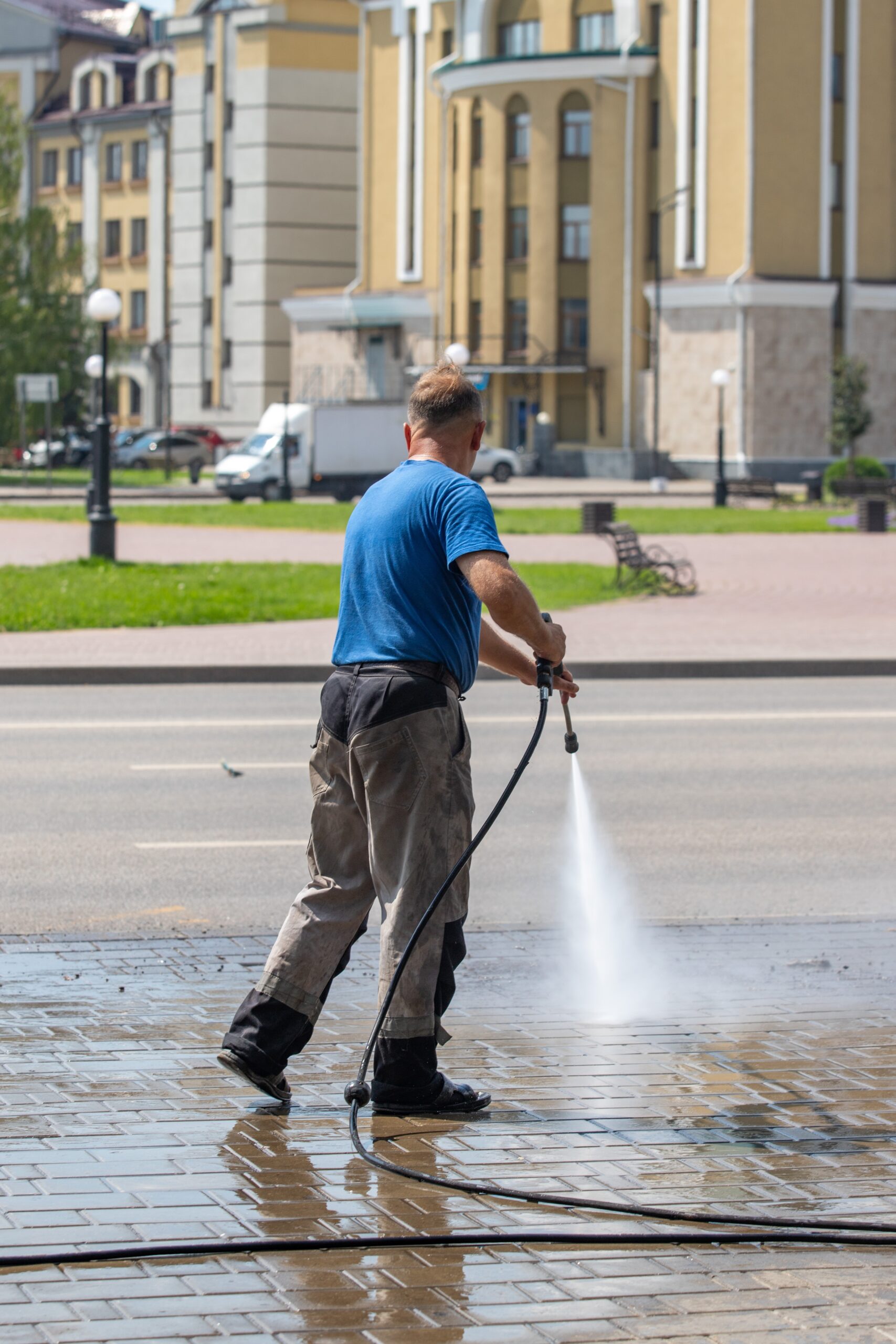 A,Man,In,A,Blue,Shirt,Is,Washing,A,Sidewalk